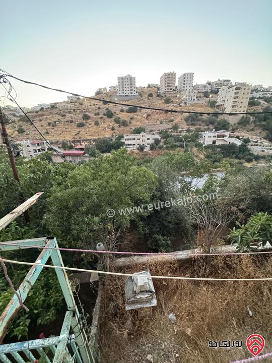 قطعة أرض تجارية مساحة 961م عليها بيت طابقين للبيع في السلط على الشارع الرئيسي مباشرة